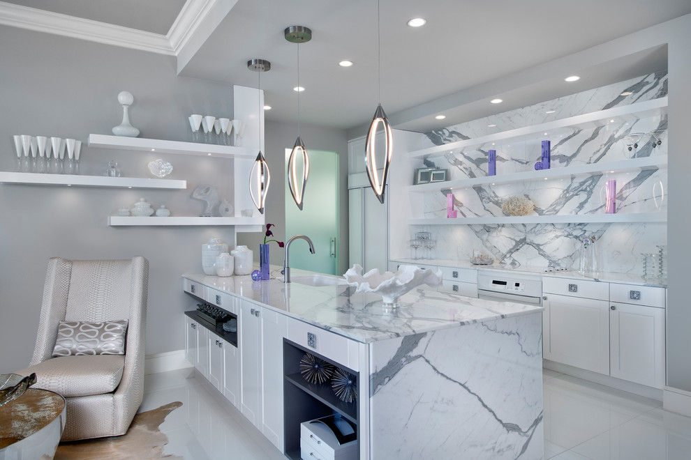 Cette image montre une cuisine parallèle design avec un évier encastré, un placard à porte shaker, des portes de placard blanches, une crédence blanche, une crédence en dalle de pierre, une péninsule et un sol blanc.