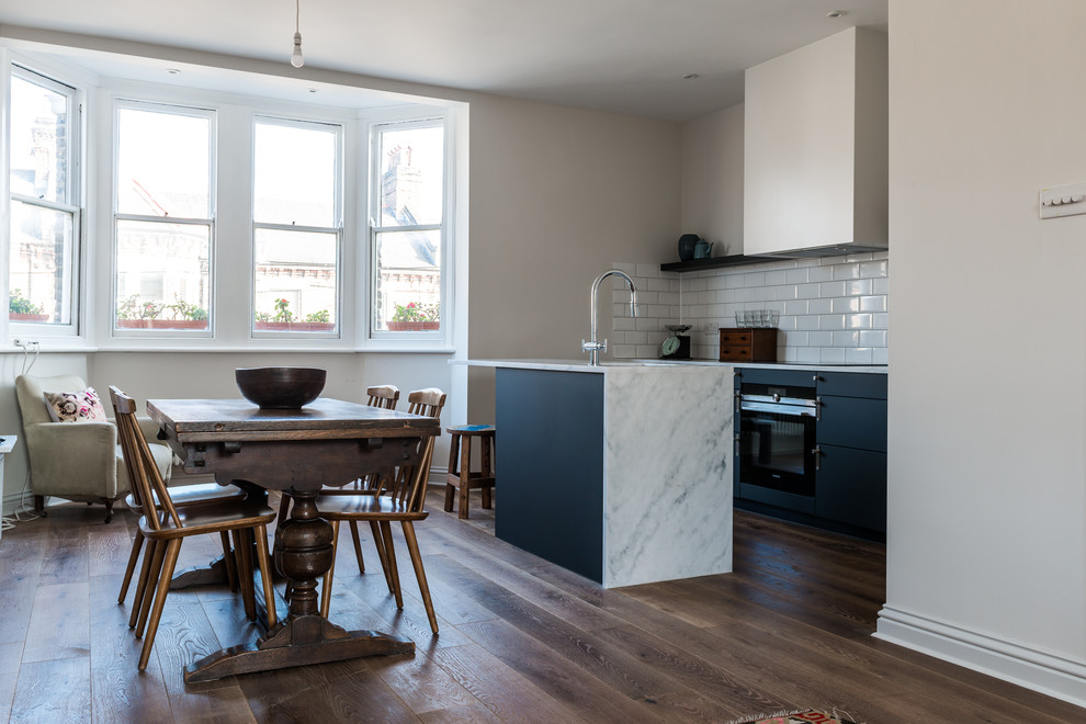 Inredning av ett skandinaviskt litet kök, med en nedsänkt diskho, luckor med infälld panel, svarta skåp, marmorbänkskiva, vitt stänkskydd, stänkskydd i cementkakel, rostfria vitvaror, mörkt trägolv och en köksö