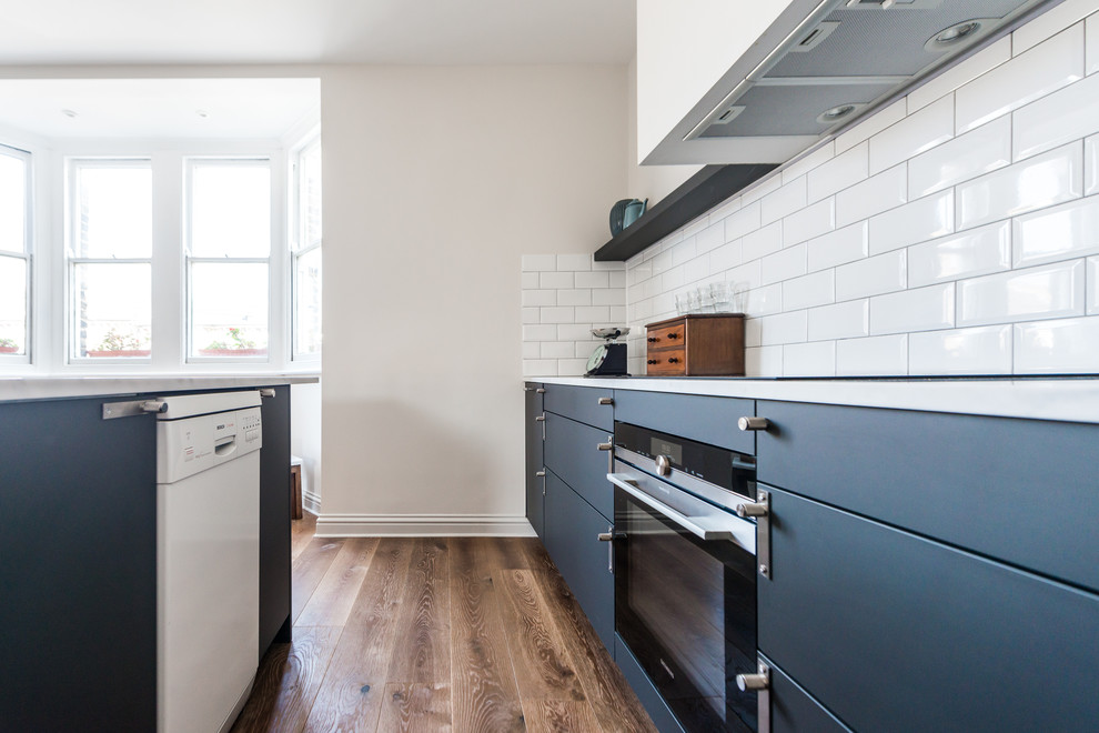 Photo of a small scandinavian u-shaped open plan kitchen in London with a built-in sink, recessed-panel cabinets, black cabinets, marble worktops, white splashback, cement tile splashback, stainless steel appliances, dark hardwood flooring and an island.