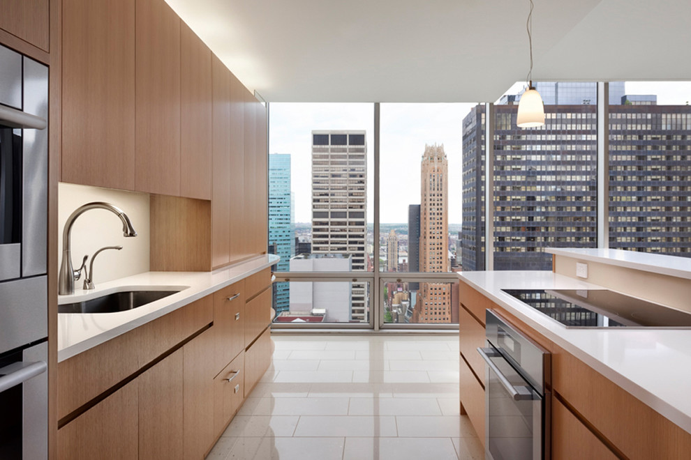 ニューヨークにあるコンテンポラリースタイルのおしゃれなキッチン (アンダーカウンターシンク、フラットパネル扉のキャビネット、中間色木目調キャビネット、白いキッチンパネル、シルバーの調理設備) の写真