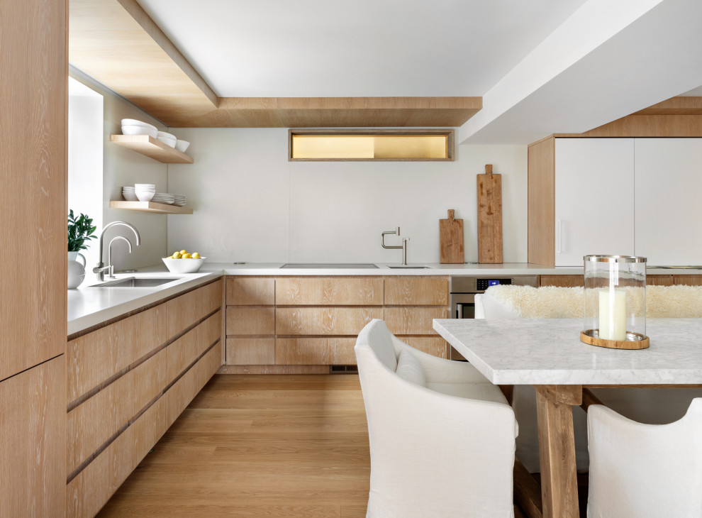 Eat-in kitchen - large contemporary l-shaped beige floor eat-in kitchen idea in New York with an undermount sink, flat-panel cabinets, light wood cabinets, paneled appliances, no island and white countertops