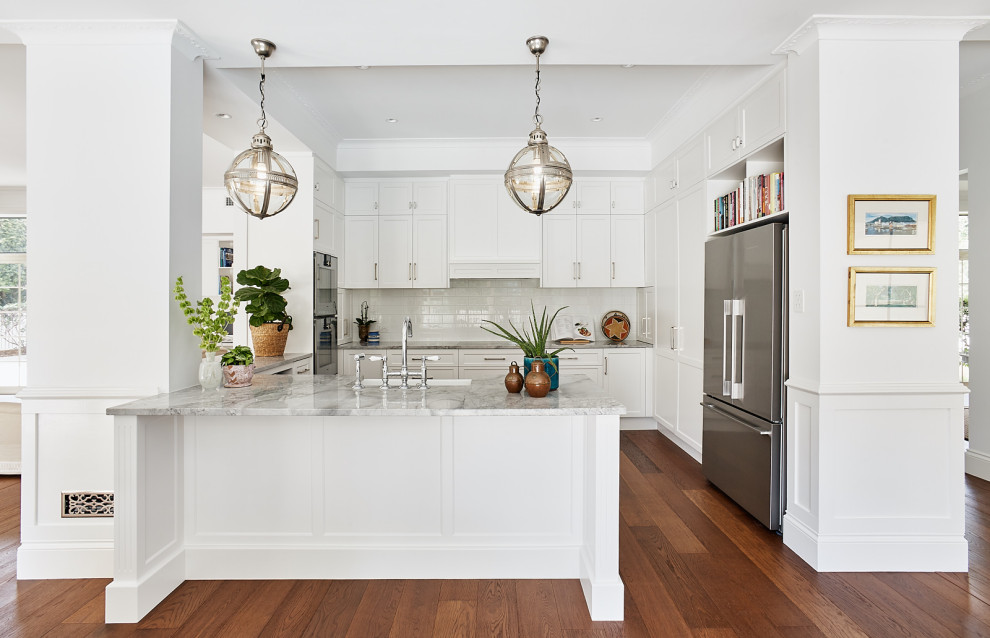 Klassische Küche mit Marmor-Arbeitsplatte, integriertem Waschbecken, Schrankfronten im Shaker-Stil, weißen Schränken, Küchenrückwand in Weiß, Rückwand aus Metrofliesen, braunem Holzboden, Kücheninsel und bunter Arbeitsplatte in Brisbane