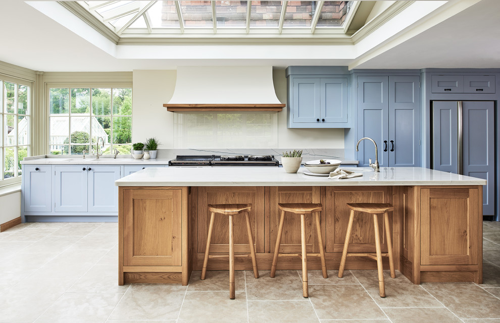 Exemple d'une cuisine parallèle et encastrable nature avec un placard à porte shaker, des portes de placard bleues, îlot, un sol beige, un plan de travail blanc et plafond verrière.