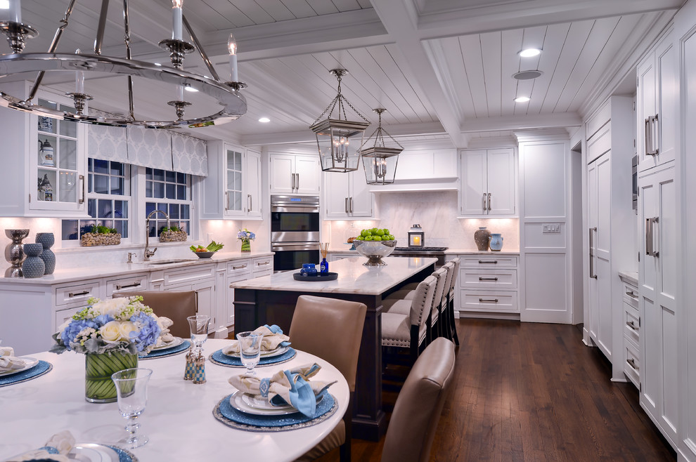 Exempel på ett stort klassiskt kök och matrum, med vita skåp, marmorbänkskiva, vitt stänkskydd, rostfria vitvaror, mörkt trägolv och en köksö