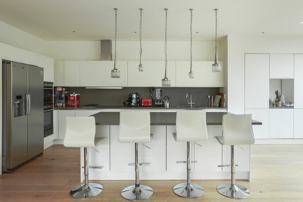 Esempio di una cucina design di medie dimensioni con lavello a doppia vasca, ante lisce, ante bianche, paraspruzzi grigio, elettrodomestici in acciaio inossidabile, parquet chiaro e pavimento beige