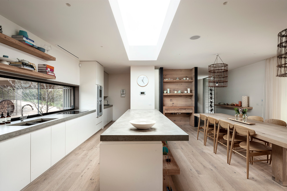 Moderne Küche mit hellem Holzboden, Unterbauwaschbecken, flächenbündigen Schrankfronten, weißen Schränken und Halbinsel in Melbourne
