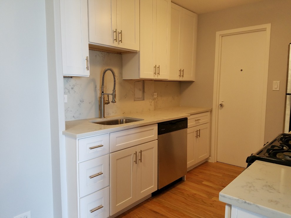 Example of a small trendy galley medium tone wood floor and brown floor enclosed kitchen design in Chicago with an undermount sink, shaker cabinets, white cabinets, quartz countertops, white backsplash, stone slab backsplash, stainless steel appliances, no island and white countertops