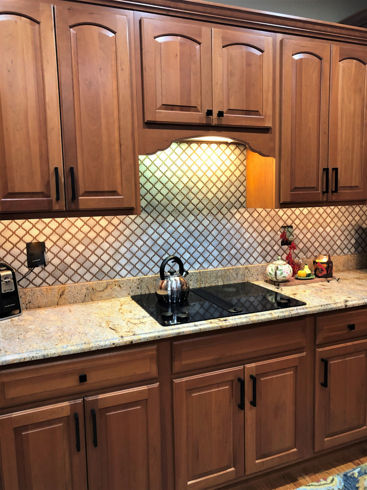 Medium sized classic kitchen in Baltimore with a built-in sink, raised-panel cabinets, granite worktops, grey splashback, glass tiled splashback, black appliances and beige worktops.