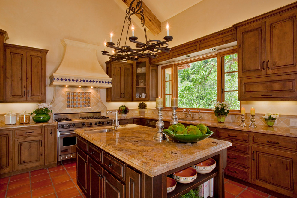 Immagine di una cucina mediterranea con top in granito, ante con bugna sagomata, ante in legno scuro, paraspruzzi beige e elettrodomestici in acciaio inossidabile