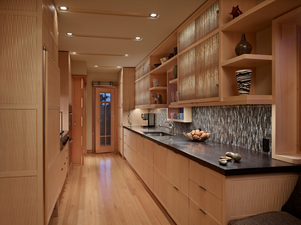 Foto på ett litet funkis kök, med en undermonterad diskho, skåp i ljust trä, bänkskiva i kalksten, integrerade vitvaror och ljust trägolv