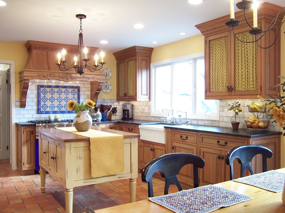 Inspiration for a mid-sized country u-shaped ceramic tile eat-in kitchen remodel in Philadelphia with a farmhouse sink, raised-panel cabinets, medium tone wood cabinets, soapstone countertops, white backsplash, subway tile backsplash, paneled appliances and an island