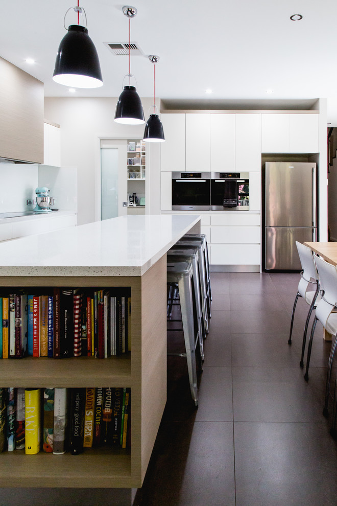 Große Moderne Küche in L-Form mit Doppelwaschbecken, flächenbündigen Schrankfronten, weißen Schränken, Quarzwerkstein-Arbeitsplatte, Küchenrückwand in Weiß, Glasrückwand, Küchengeräten aus Edelstahl, Keramikboden und Kücheninsel in Canberra - Queanbeyan