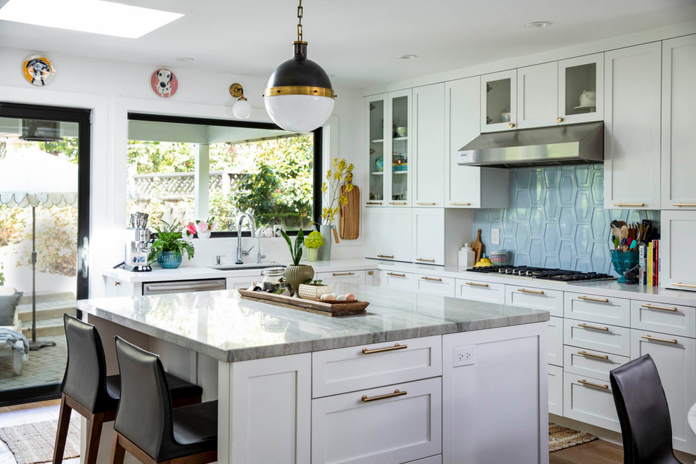 Inredning av ett klassiskt mellanstort grå grått kök, med en undermonterad diskho, skåp i shakerstil, vita skåp, bänkskiva i kvartsit, blått stänkskydd, stänkskydd i keramik, mellanmörkt trägolv, en köksö, rostfria vitvaror och brunt golv