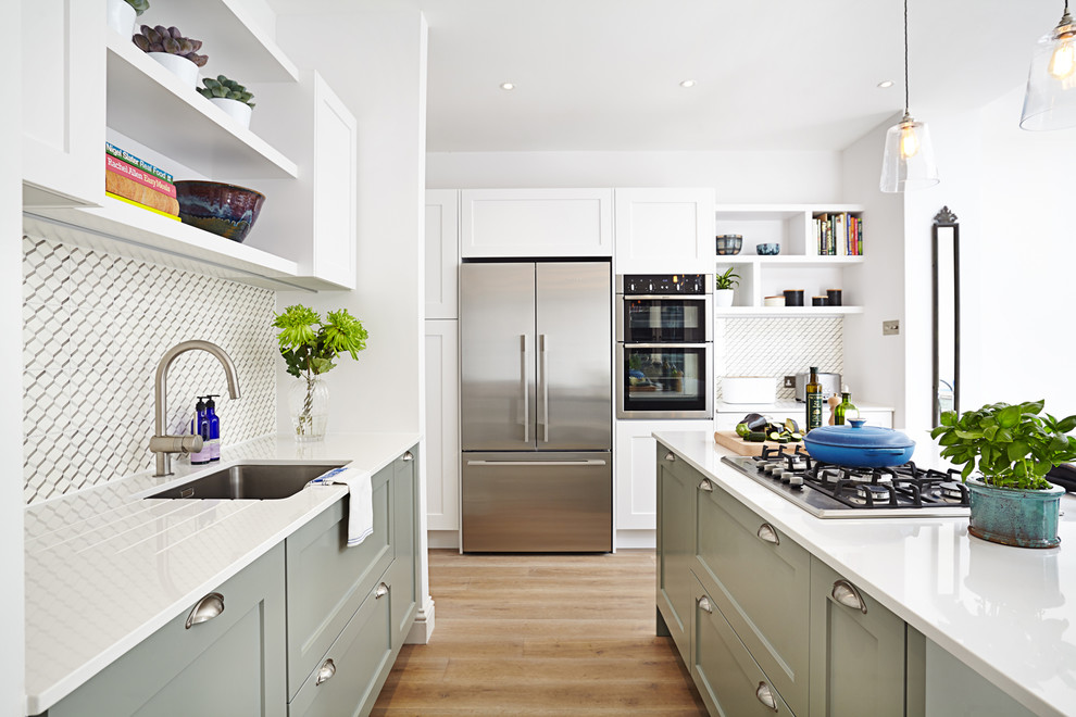 Classic kitchen in London with a submerged sink, shaker cabinets, green cabinets, multi-coloured splashback, stainless steel appliances, medium hardwood flooring, an island and beige floors.