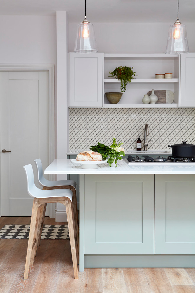 Klassische Küche mit Schrankfronten mit vertiefter Füllung, blauen Schränken, hellem Holzboden, Kücheninsel und beigem Boden in London