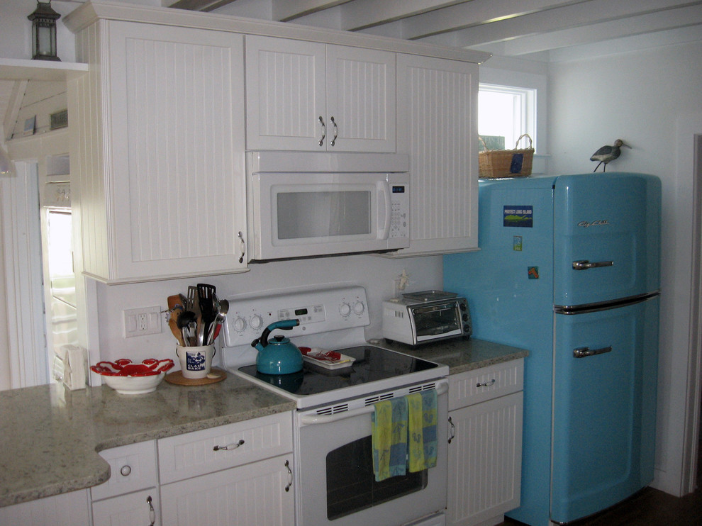 ニューヨークにある高級な小さなビーチスタイルのおしゃれなキッチン (エプロンフロントシンク、シェーカースタイル扉のキャビネット、白いキャビネット、白い調理設備) の写真
