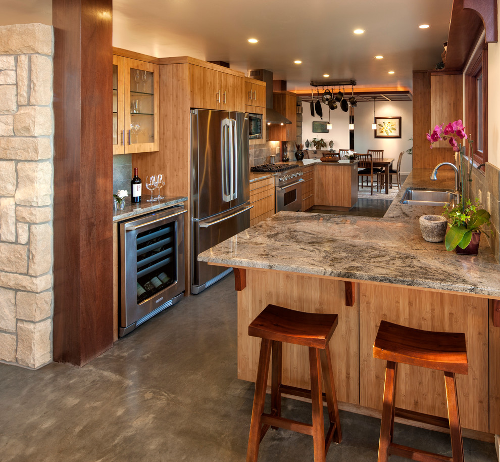 Large trendy galley concrete floor kitchen photo in Santa Barbara with a double-bowl sink, flat-panel cabinets, medium tone wood cabinets, brown backsplash, stone tile backsplash and stainless steel appliances