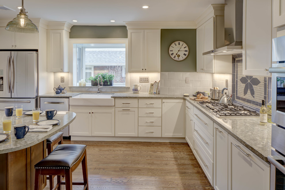 Mid-sized transitional medium tone wood floor and brown floor eat-in kitchen photo in New York with a farmhouse sink, shaker cabinets, white cabinets, quartz countertops, multicolored backsplash, ceramic backsplash and stainless steel appliances