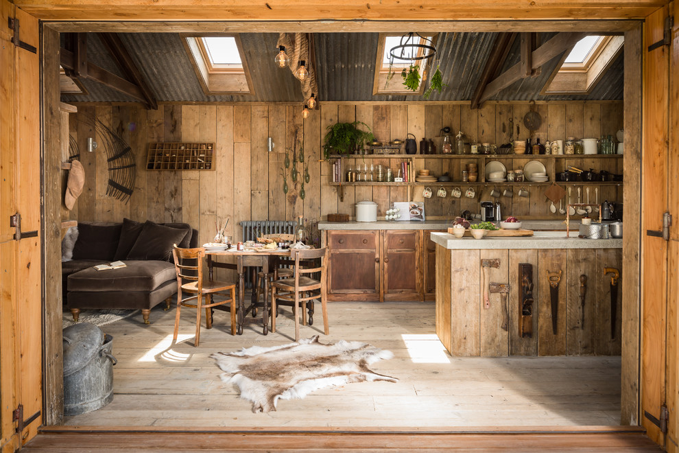 Design ideas for a small rustic galley kitchen/diner in Cornwall with a belfast sink, beaded cabinets, medium wood cabinets, integrated appliances, light hardwood flooring and concrete worktops.