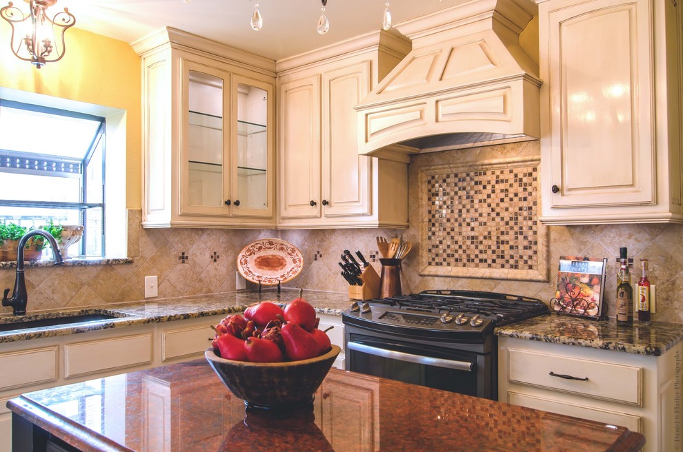 Example of a large classic u-shaped porcelain tile eat-in kitchen design in Dallas with a double-bowl sink, raised-panel cabinets, distressed cabinets, granite countertops, beige backsplash, mosaic tile backsplash, colored appliances and an island