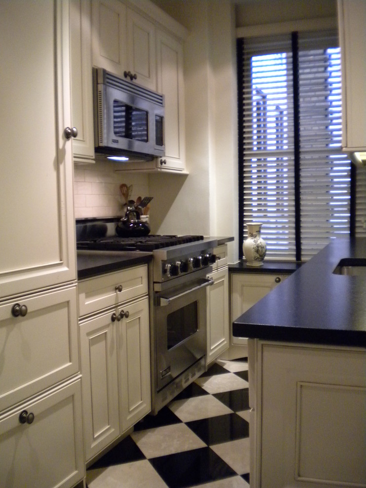 Photo of a small traditional galley kitchen/diner in New York with a single-bowl sink, recessed-panel cabinets, white cabinets, granite worktops, white splashback, ceramic splashback, stainless steel appliances, marble flooring and no island.