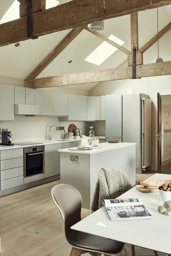 Example of an urban single-wall light wood floor and beige floor eat-in kitchen design in Other with flat-panel cabinets, gray cabinets, white backsplash, stainless steel appliances and an island