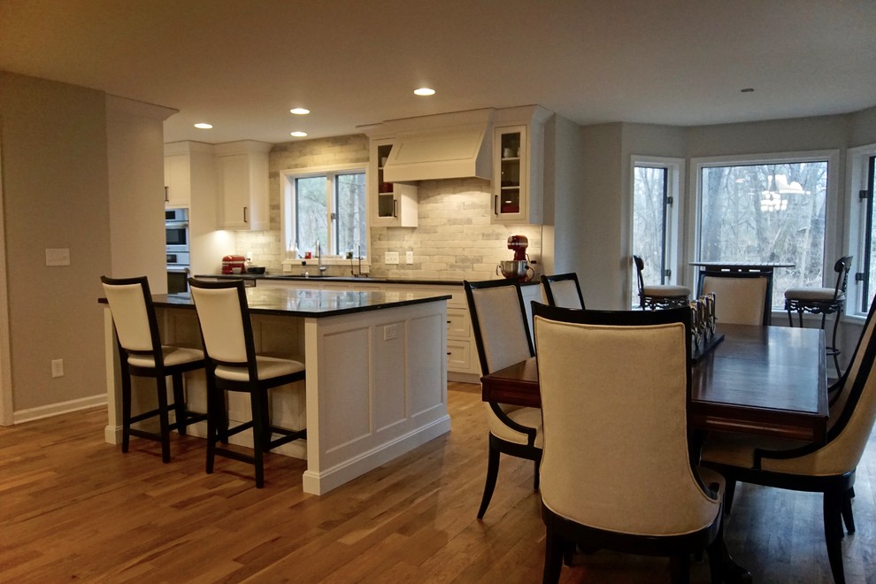 Example of a large transitional medium tone wood floor open concept kitchen design in Indianapolis with an undermount sink, beaded inset cabinets, white cabinets, soapstone countertops, white backsplash, stone slab backsplash, stainless steel appliances and an island