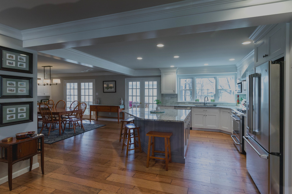Modern inredning av ett mellanstort flerfärgad flerfärgat kök, med en undermonterad diskho, släta luckor, vita skåp, granitbänkskiva, vitt stänkskydd, stänkskydd i tunnelbanekakel, rostfria vitvaror, mellanmörkt trägolv, en köksö och flerfärgat golv