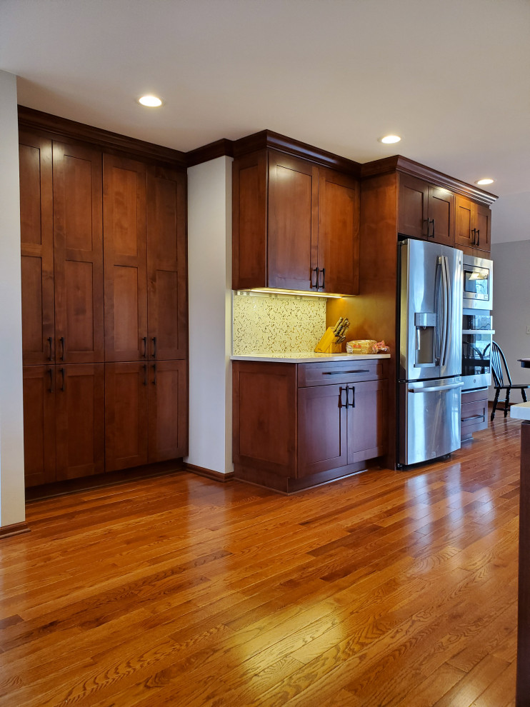 Exempel på ett avskilt, mellanstort klassiskt vit linjärt vitt kök, med en undermonterad diskho, skåp i shakerstil, skåp i mellenmörkt trä, bänkskiva i kvarts, flerfärgad stänkskydd, rostfria vitvaror, mellanmörkt trägolv, en köksö och brunt golv