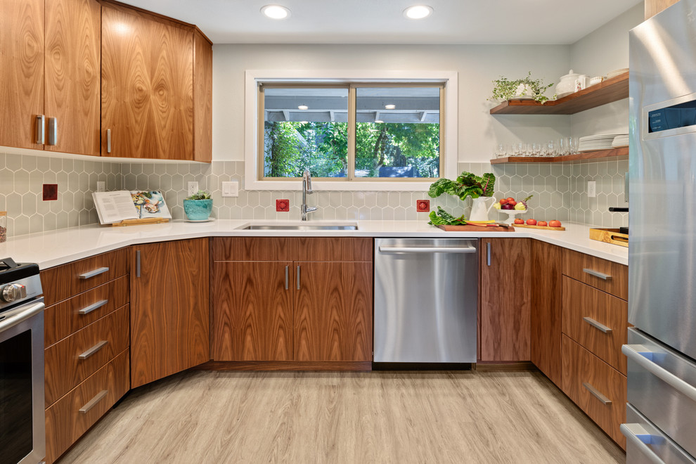 Bild på ett 50 tals vit vitt kök, med en enkel diskho, släta luckor, skåp i mellenmörkt trä, bänkskiva i kvarts, grått stänkskydd, stänkskydd i porslinskakel, rostfria vitvaror och vinylgolv