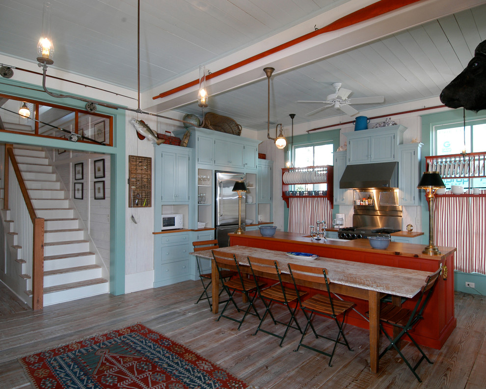 Foto på ett maritimt kök och matrum, med rostfria vitvaror, luckor med infälld panel, blå skåp och träbänkskiva