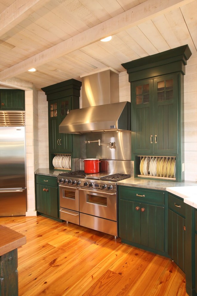 Foto di una grande cucina stile rurale con lavello da incasso, ante verdi, paraspruzzi bianco, elettrodomestici in acciaio inossidabile, pavimento in legno massello medio e top in acciaio inossidabile