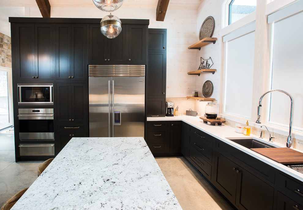 Large beach style u-shaped open plan kitchen in Minneapolis with a submerged sink, shaker cabinets, grey cabinets, engineered stone countertops, beige splashback, stone tiled splashback, stainless steel appliances, concrete flooring and an island.