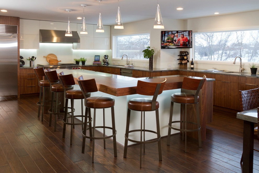 This is an example of a large contemporary l-shaped kitchen/diner in Minneapolis with a submerged sink, flat-panel cabinets, medium wood cabinets, granite worktops, white splashback, glass sheet splashback, stainless steel appliances, dark hardwood flooring and an island.
