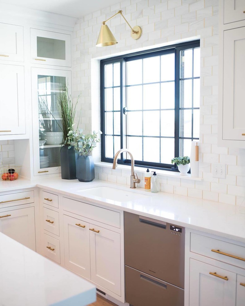 Bild på ett mellanstort funkis vit linjärt vitt kök, med en undermonterad diskho, skåp i shakerstil, vita skåp, vitt stänkskydd, stänkskydd i marmor, rostfria vitvaror, mellanmörkt trägolv, en köksö och brunt golv