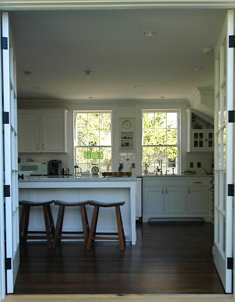 Imagen de cocina lineal clásica de tamaño medio cerrada con armarios con paneles lisos, puertas de armario blancas y una isla
