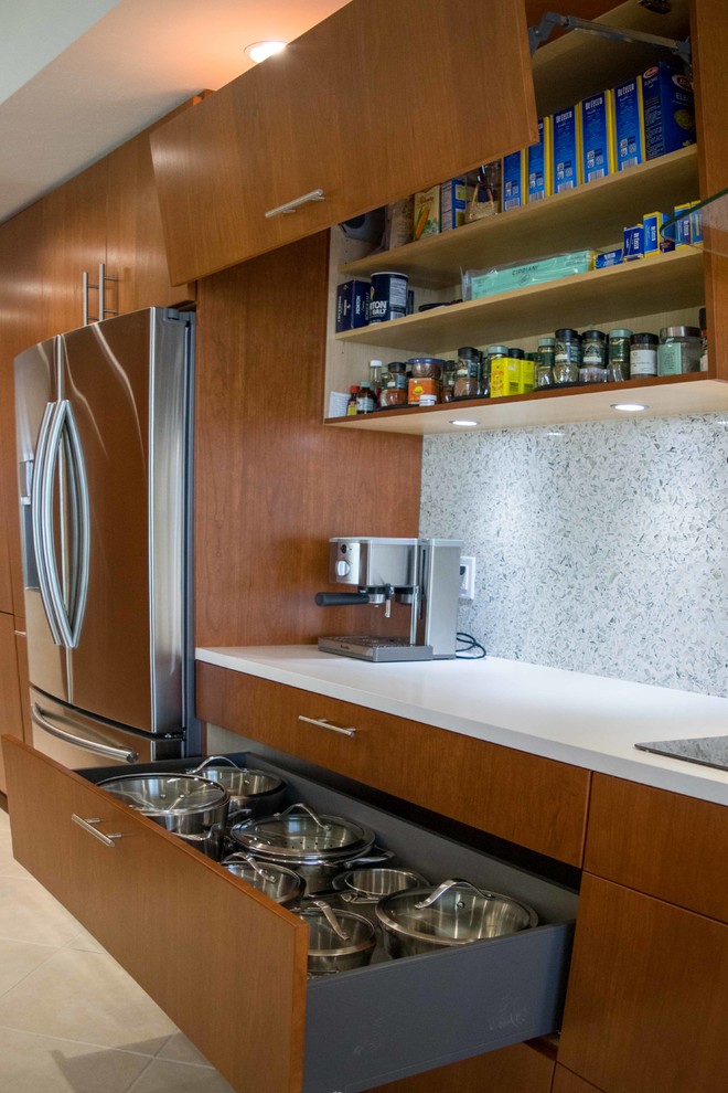 マイアミにある高級な中くらいなコンテンポラリースタイルのおしゃれなキッチン (ダブルシンク、フラットパネル扉のキャビネット、中間色木目調キャビネット、クオーツストーンカウンター、白いキッチンパネル、シルバーの調理設備、磁器タイルの床、大理石のキッチンパネル、アイランドなし、ベージュの床) の写真