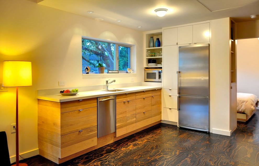 Источник вдохновения для домашнего уюта: угловая кухня-гостиная в современном стиле с врезной мойкой, плоскими фасадами, светлыми деревянными фасадами и техникой из нержавеющей стали