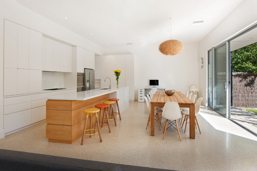 Example of a mid-sized trendy galley concrete floor eat-in kitchen design in Adelaide with an undermount sink, stainless steel appliances, an island, white cabinets, quartz countertops and white backsplash