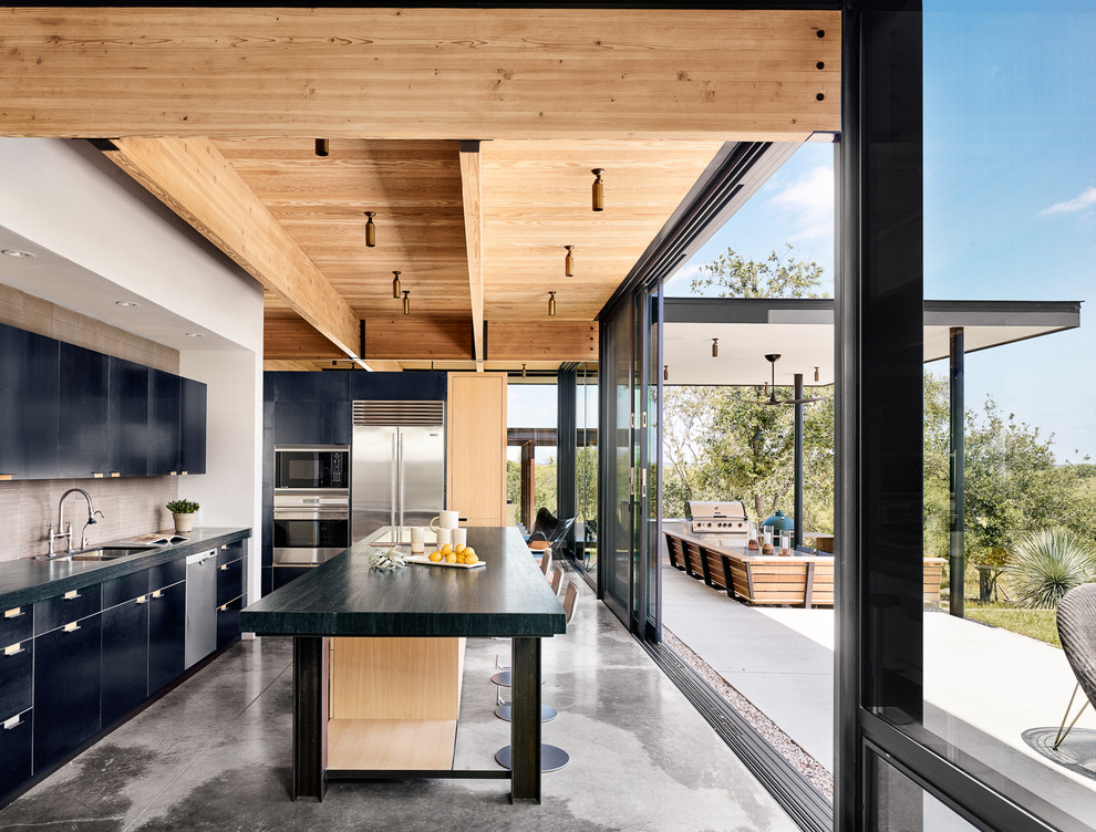 Example of a large trendy l-shaped concrete floor kitchen design in Austin with a double-bowl sink, flat-panel cabinets, black cabinets, gray backsplash, stainless steel appliances and an island