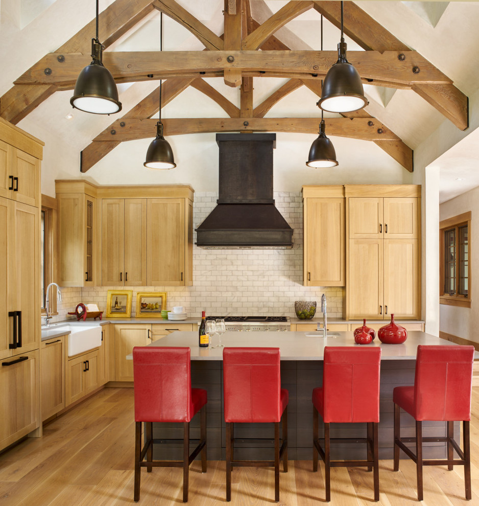 Bild på ett rustikt l-kök, med en undermonterad diskho, skåp i shakerstil, skåp i ljust trä, vitt stänkskydd, stänkskydd i tunnelbanekakel, ljust trägolv, en köksö, beiget golv och integrerade vitvaror