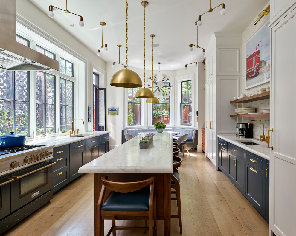 Eat-in kitchen - transitional galley light wood floor and beige floor eat-in kitchen idea in Philadelphia with an undermount sink, shaker cabinets, blue cabinets, white backsplash, brick backsplash, an island and white countertops