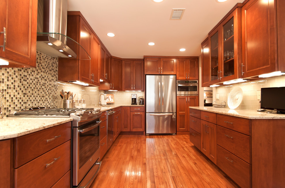 Example of a trendy galley kitchen design in DC Metro with medium tone wood cabinets, quartz countertops, green backsplash, glass tile backsplash and stainless steel appliances