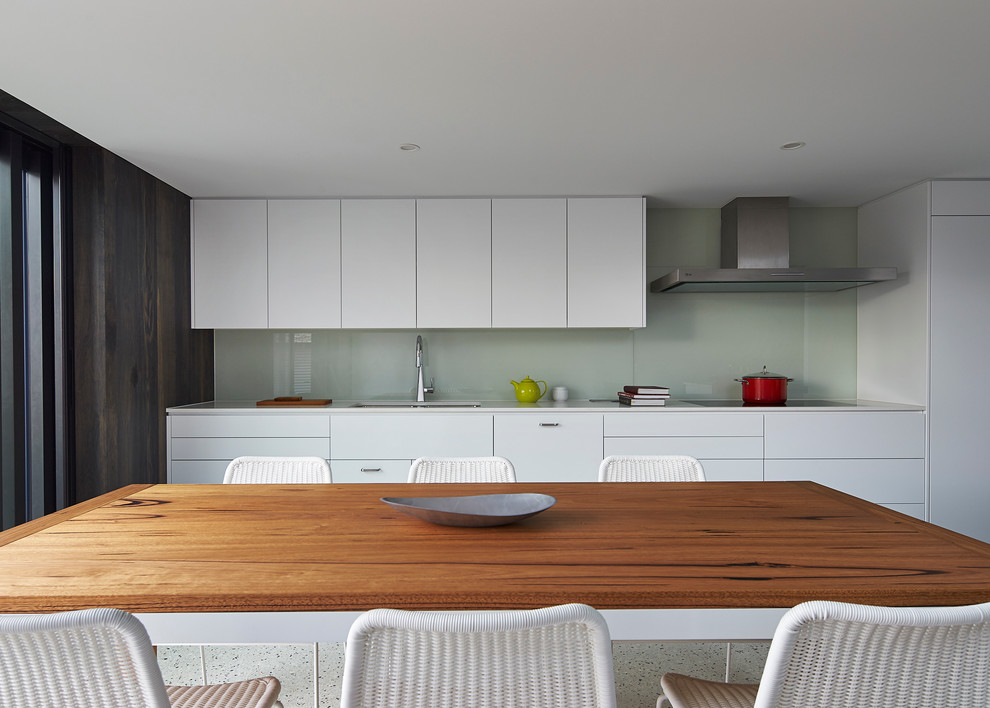 Exempel på ett modernt kök och matrum, med en undermonterad diskho, vita skåp, bänkskiva i kvarts, vitt stänkskydd, glaspanel som stänkskydd, integrerade vitvaror och betonggolv