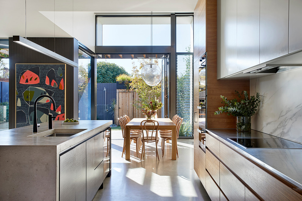 Exempel på ett modernt grå grått kök, med en undermonterad diskho, släta luckor, skåp i ljust trä, bänkskiva i betong, beige stänkskydd, stänkskydd i marmor, svarta vitvaror, betonggolv, en köksö och grått golv