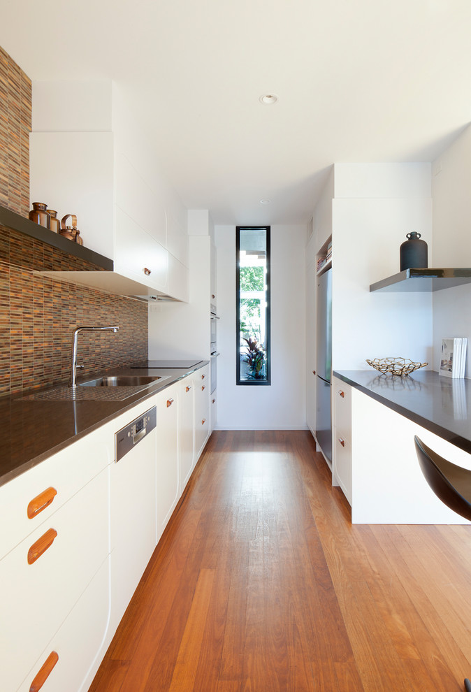 Photo of a medium sized contemporary galley kitchen/diner in Melbourne with a built-in sink, shaker cabinets, beige cabinets, multi-coloured splashback, matchstick tiled splashback, stainless steel appliances, medium hardwood flooring, an island, beige floors and grey worktops.