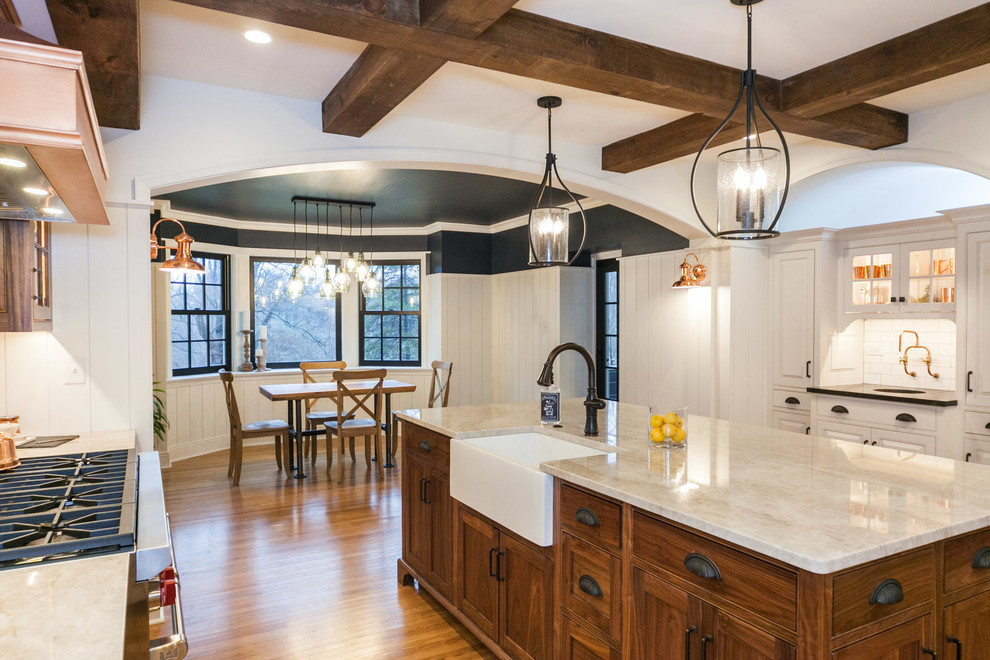 1950s u-shaped medium tone wood floor and brown floor enclosed kitchen photo in Other with a farmhouse sink, raised-panel cabinets, white cabinets, white backsplash, subway tile backsplash, stainless steel appliances, an island and white countertops