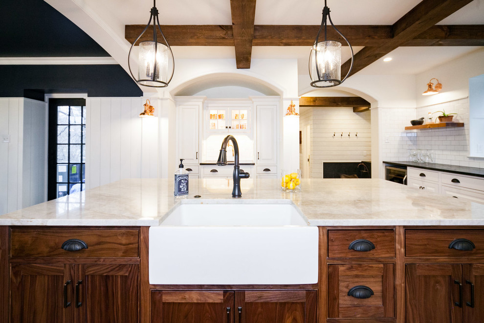 Example of a 1960s u-shaped medium tone wood floor and brown floor enclosed kitchen design in Other with a farmhouse sink, raised-panel cabinets, white cabinets, white backsplash, subway tile backsplash, stainless steel appliances, an island and white countertops