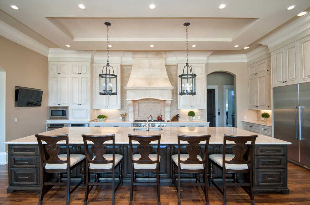 Inspiration for a huge timeless dark wood floor kitchen remodel in Other with a single-bowl sink, raised-panel cabinets, beige cabinets, granite countertops, beige backsplash, stone tile backsplash, stainless steel appliances and an island