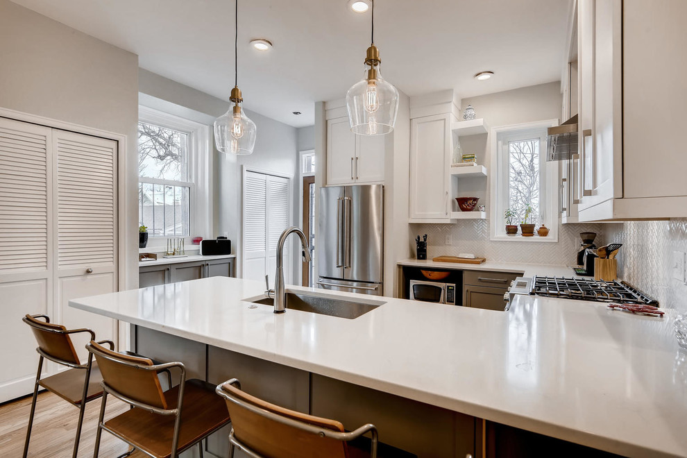 Klassisk inredning av ett litet vit vitt kök, med en undermonterad diskho, skåp i shakerstil, vita skåp, granitbänkskiva, vitt stänkskydd, stänkskydd i keramik, rostfria vitvaror, ljust trägolv, en halv köksö och brunt golv